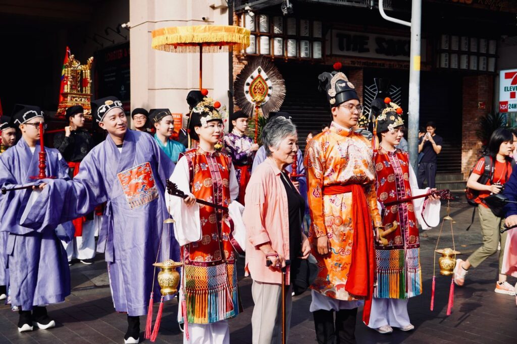Eine Gruppe von Personen in traditioneller chinesischer Kleidung, die zusammenstehen und lächeln.