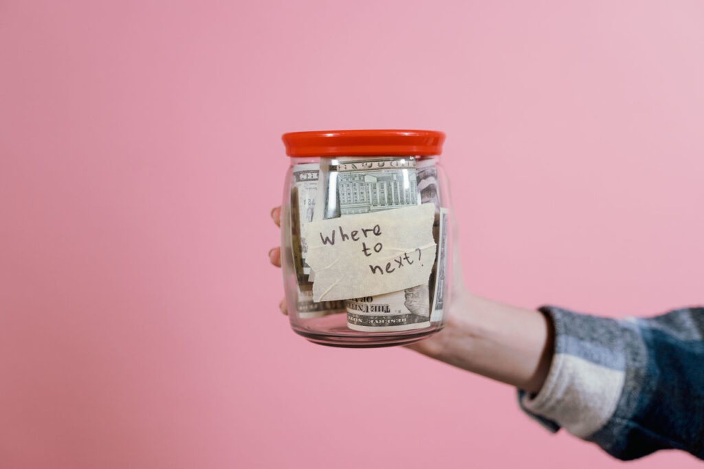 https://www.pexels.com/de-de/foto/hand-geld-festhalten-halten-7009864/ Ein Glas mit Geldscheinen und einer Notiz darauf, die Zweck des Geldes beschreibt.